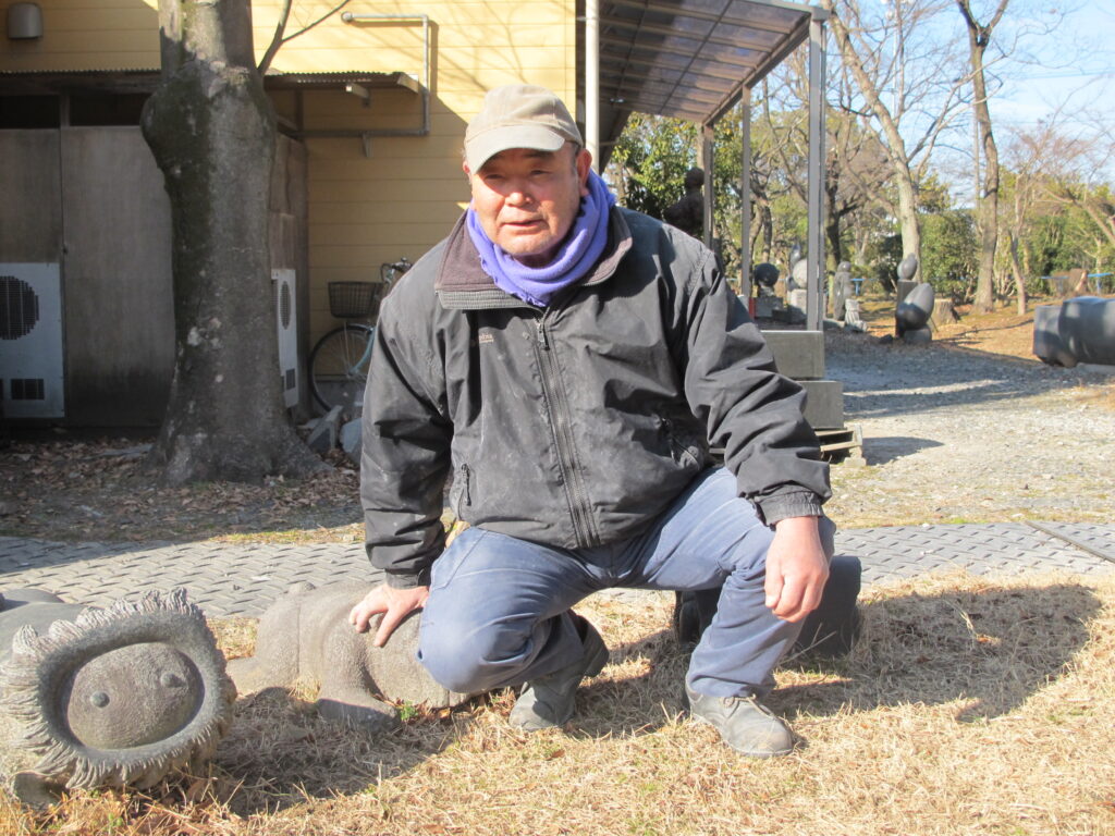 伊佐沼工房前に座った田中毅さん